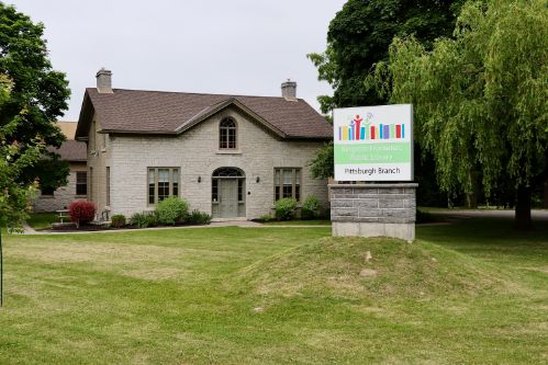 Limestone building, grass lawn and logo sign. 