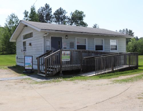 Small building in a field with wooden ramp at the front and sign for Plevna on the railing