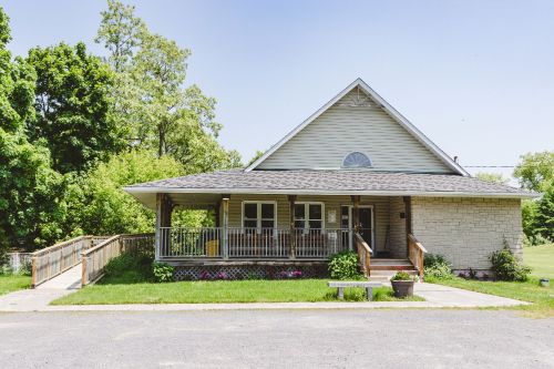 Small white house with green lawn and accessible wooden ramp on the left