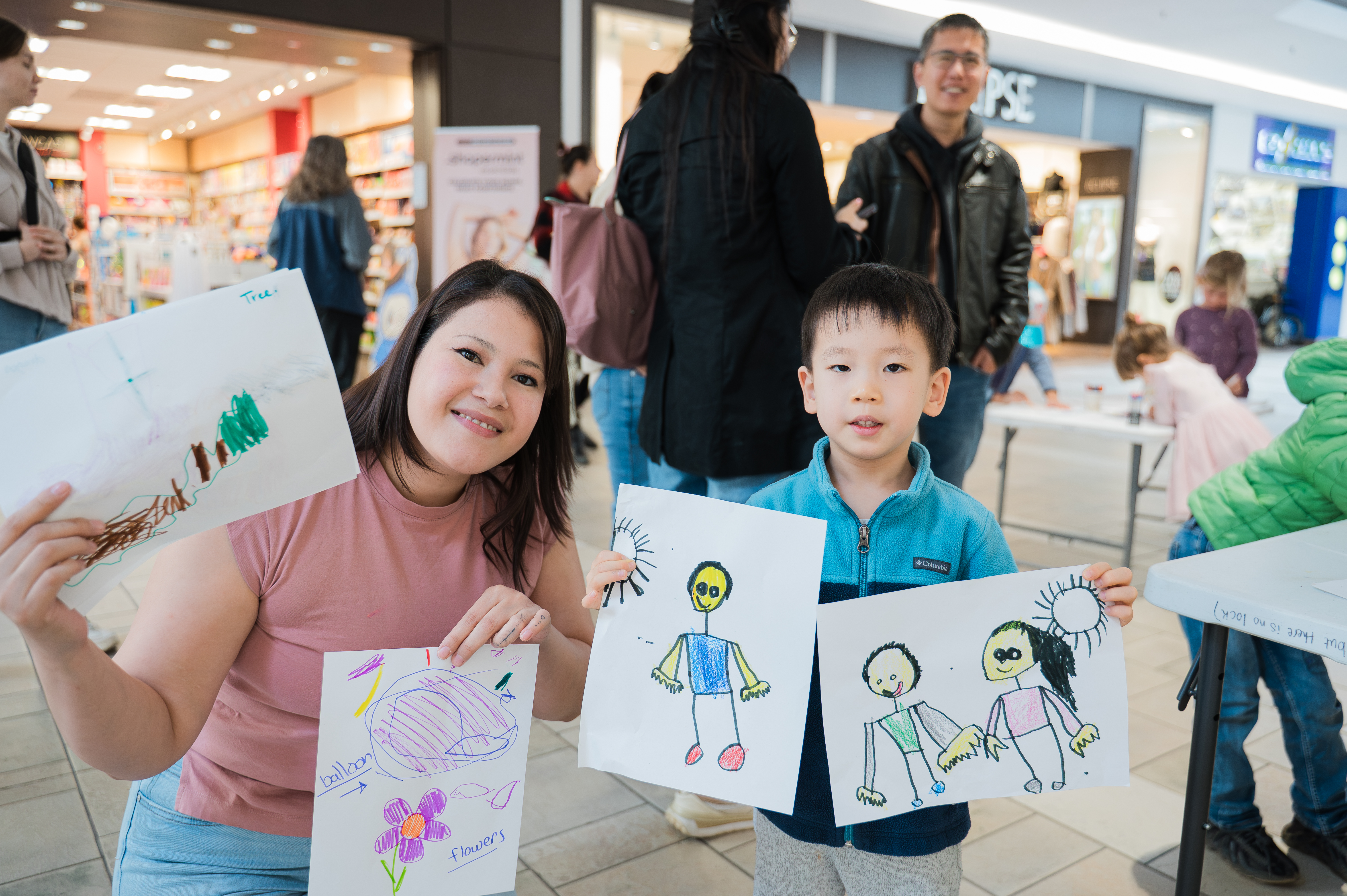 A woman and young child show off their drawings of people