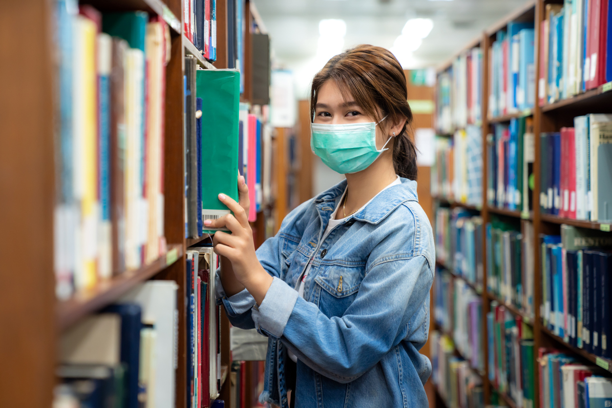person looking for a book with a mask on